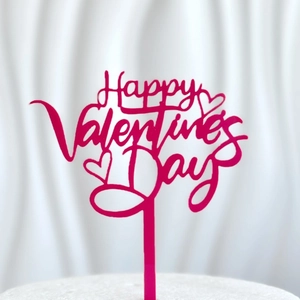 Close-up of pink Happy Valentine's Day acrylic cake topper with cursive text and heart motifs