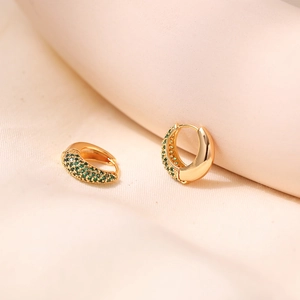 Macro view of 18K gold plated brass earrings with pavé-set green cubic zirconia stones