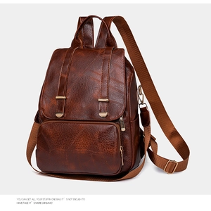 Detailaufnahme der braunen Lederrucksack-Textur mit goldenem Reißverschluss und Schnallen