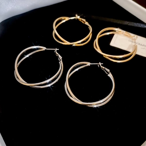 Nahaufnahme von gold- und silberfarbenen doppelschichtigen Creolen auf schwarzem Samt