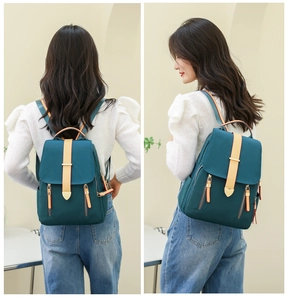 Detail view of a dark teal waterproof oxford backpack featuring leather zipper accents