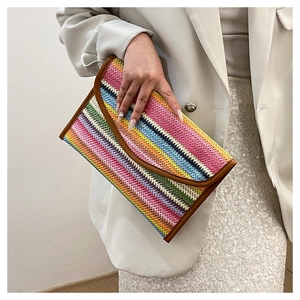 Detail of colorful striped straw clutch bag with gold metal snap and brown faux leather trim