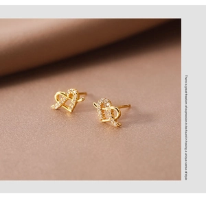 Close-up of heart-shaped gold stud earrings with pavé white zircon stone settings
