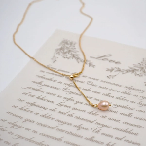 Collier en Y ajustable doré avec perle rose en forme de goutte sur fond rétro élégant