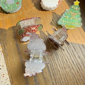 Flat lay of colorful Christmas tree and snowflake hair clips on a wooden surface