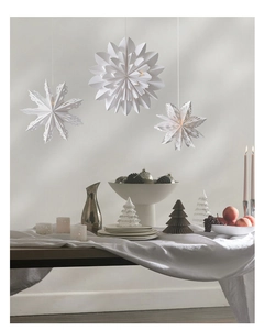 Close-up of white paper snowflake ornaments hanging above an elegant dining table
