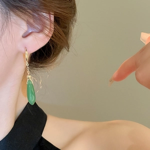 Close-up of gold plated long teardrop earrings with emerald green glaze and zircons