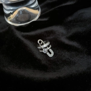 Macro view of silver paperclip ear cuff with white zircons on black velvet background