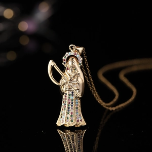 Pendentif Santa Muerte doré avec zircons colorés sur une surface noire réfléchissante
