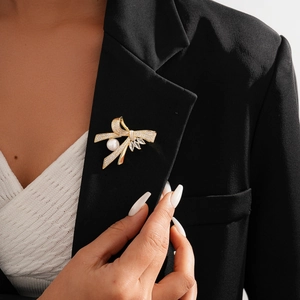 Close-up of a 14k gold-plated bow brooch with pearls and zircons on a black blazer lapel