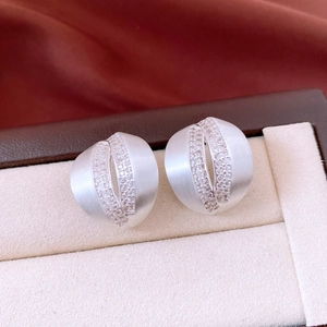 Macro shot of silver C-shape earrings with brushed finish and zircon inlay details