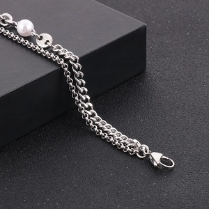 Macro view of double-layer stainless steel chain bracelet with white pearl and lobster clasp