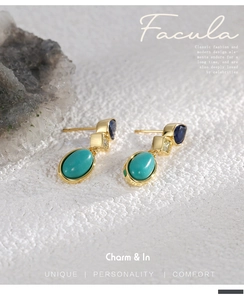 Detailed close-up of teardrop blue zircon and turquoise earrings on a stone base