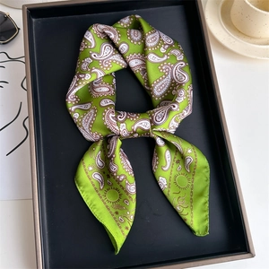 Elegant green silk-like square scarf with paisley pattern displayed on a tray