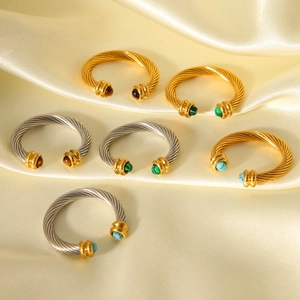 Détail de bagues torsadées avec malachite et turquoise sur un tissu en soie dorée