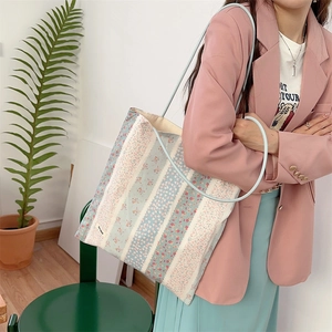 Détail du sac fourre-tout en toile patchwork fleuri avec fines anses et simple étiquette