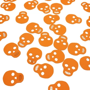 Scattered orange skull confetti decorations for Halloween party table setting and crafts