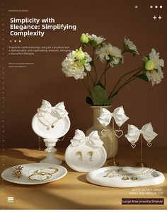 Macro view of white bow-shaped jewelry display stand with marble texture and floral accents