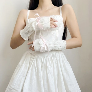 Close-up of white cable knit sleeves featuring delicate pink ribbon bows and fingerless design