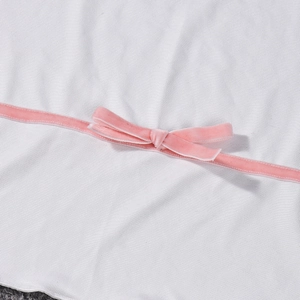 Detailed close-up of white knit fabric texture featuring a pink velvet bow decoration