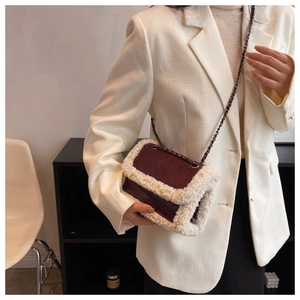 Detail of burgundy leather shoulder bag with white faux fur trim and woven chain strap