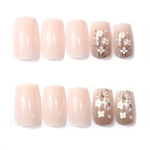 Detail of square round press-on nails with nude base and delicate white flower patterns