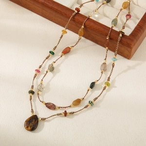 Detail of bohemian long necklace with natural tiger eye stone pendant and woven beads