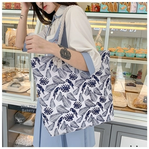 Close-up of tropical leaf print on canvas tote bag with beige rope shoulder handles