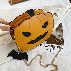 Detail of pumpkin crossbody bag with black bat charm and golden metal chain strap