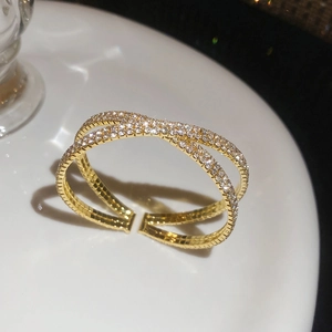 Vue macro du bracelet doré à double couche entrecroisée avec détails en zircons brillants