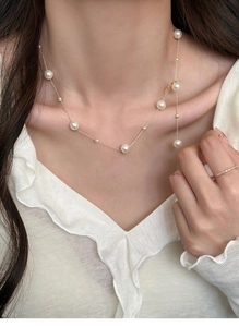 Close-up of elegant French style gold pearl necklace worn on a neck with a white blouse