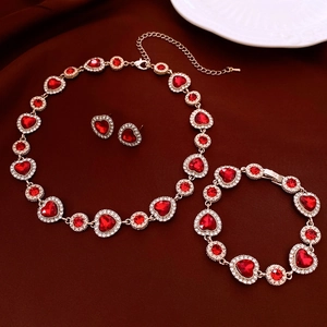 Vue détaillée d'une parure bijoux dorés avec pierres rouges en cœur et strass brillants