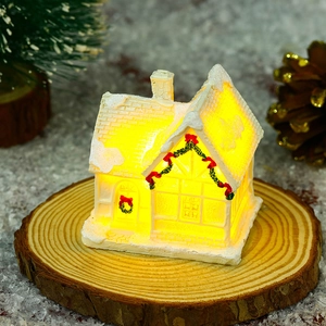 Macro view of glowing white resin Christmas village house with warm LED lights and snow decor