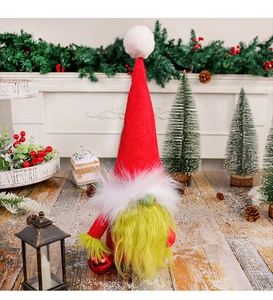 Detail of a Christmas gnome with green beard holding a red heart ball on wood