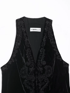 Detailed embroidery and beadwork on a black velvet vest with intricate paisley patterns