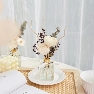 Detail of relief glass bottle reed diffuser with white ribbon and preserved dried flowers