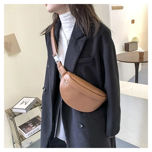 Close-up of a stylish brown leather fanny pack worn over a black autumn coat for women