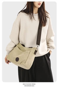 Detail of beige canvas messenger bag showing adjustable brown strap and front pocket
