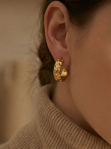 Detail of 18k gold plated stainless steel C-hoop earring with irregular hammered texture