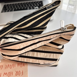 Close-up of striped makeup bags showing woven texture and durable metal zipper details