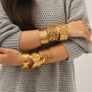 Bohemian gold plated starfish and seashell open bangle set worn on a grey knit sweater