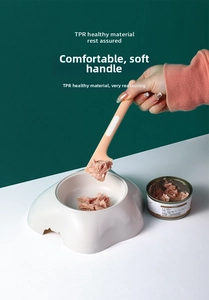 Detail showing pink TPR long-handle spoon scooping wet food into white cat bowl