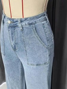 Detail van lichtblauwe high-waist jeans met wijde pijpen en grote opgestikte zakken