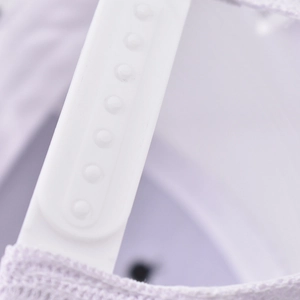 Close-up of a white plastic snapback adjustment strap on a light purple baseball cap