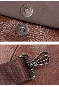 Detail of gunmetal magnetic buckle and webbing strap attachment on brown leather bag