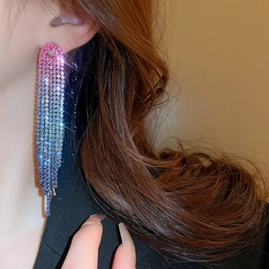 Close-up of sparkling long tassel earrings with pink-purple-blue gradient rhinestones