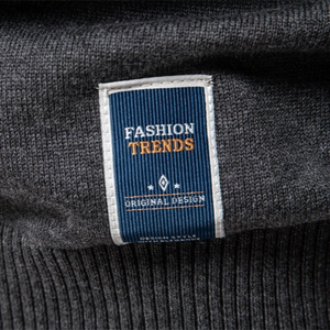 Gros plan d'une étiquette tissée bleue sur un pull en maille gris foncé pour hommes