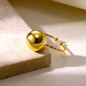 Vue macro d'une bague ouverte en acier doré avec perle et anneau torsadé détaillé