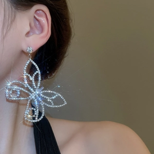 Macro shot of silver butterfly drop earring with sparkling rhinestones on a female model