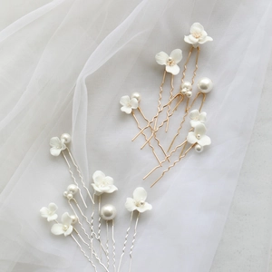 Elegant bridal hair pins set with ceramic flowers and pearls on white soft tulle background